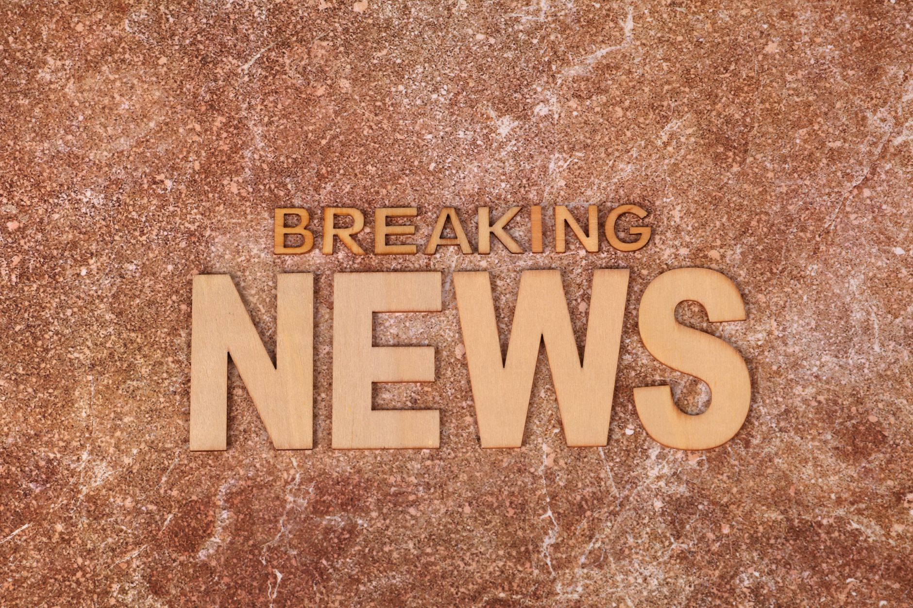 Wooden letters spell 'Breaking News' on a textured, marble-like background. Ideal for newsworthy content. — Comment profiter