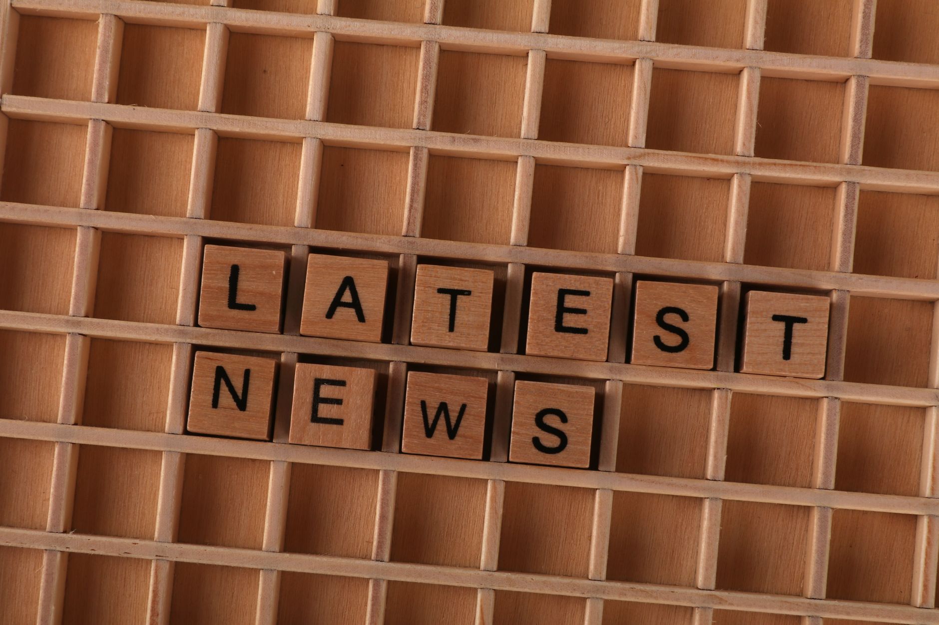 Wooden letter blocks spelling Latest News on a grid background, ideal for media themes. — Erfahrungen von ehemaligen Spielern