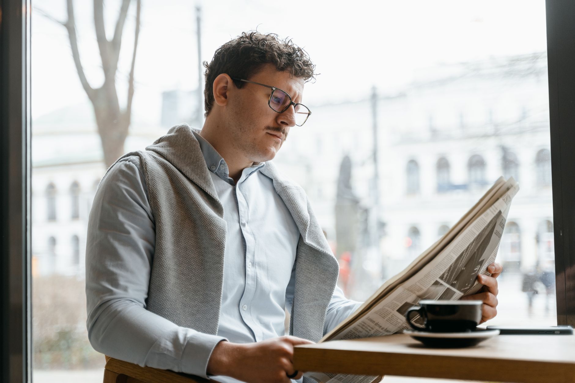 Adult man reads a newspaper by a café window, enjoying a coffee break indoors. — Roulettino Casino: Ein Erfahrungsbericht aus