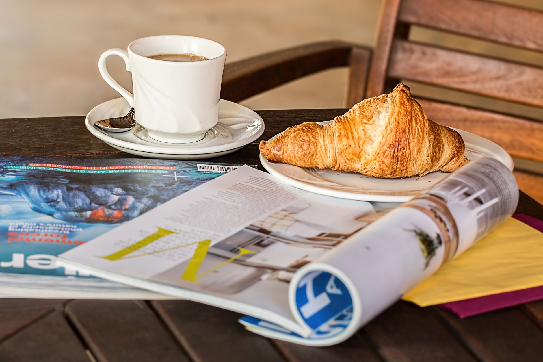Enjoy a peaceful morning with coffee, croissant, and reading material on a wooden table. — Sensible Medical insurance Prepara