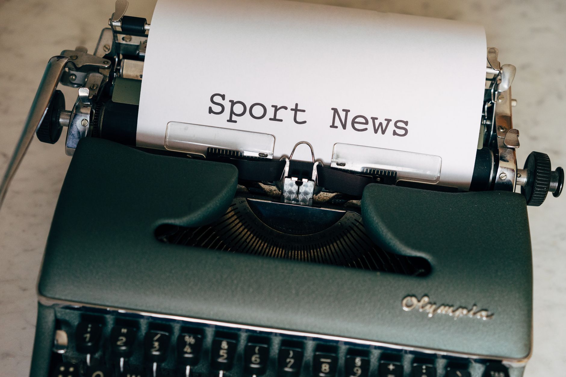 Close-up of a vintage typewriter with a paper showing 'Sport News', evoking nostalgia and classic journalism. — TonySpins Cas