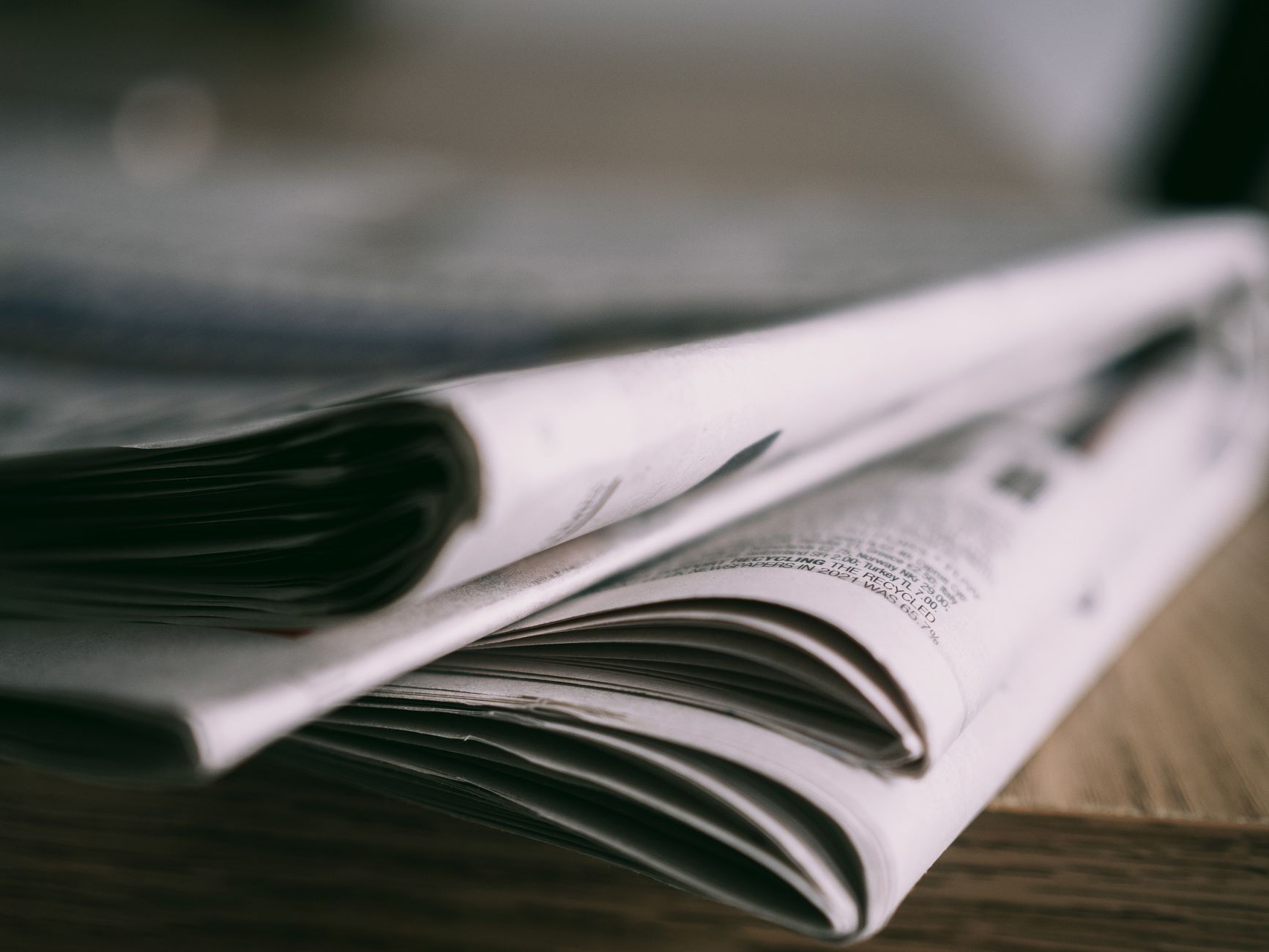 Stack of folded newspapers on a wooden table with a focus on printed pages. — Unleashing the Fun: Een Diepgaande Kijk op Spin