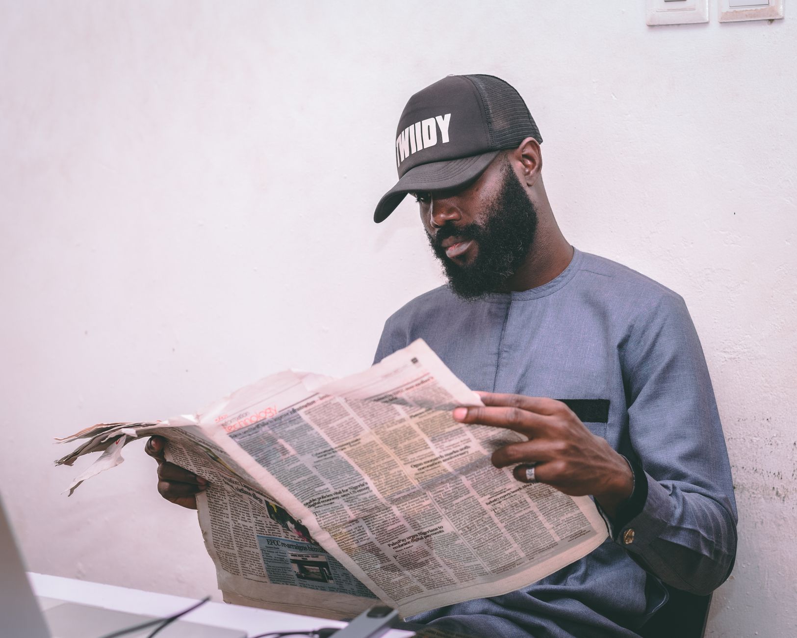 Adult man reading a newspaper indoors, wearing a cap and traditional attire. — Wie die Mobile Gaming Erfahrung im Dragon Slot