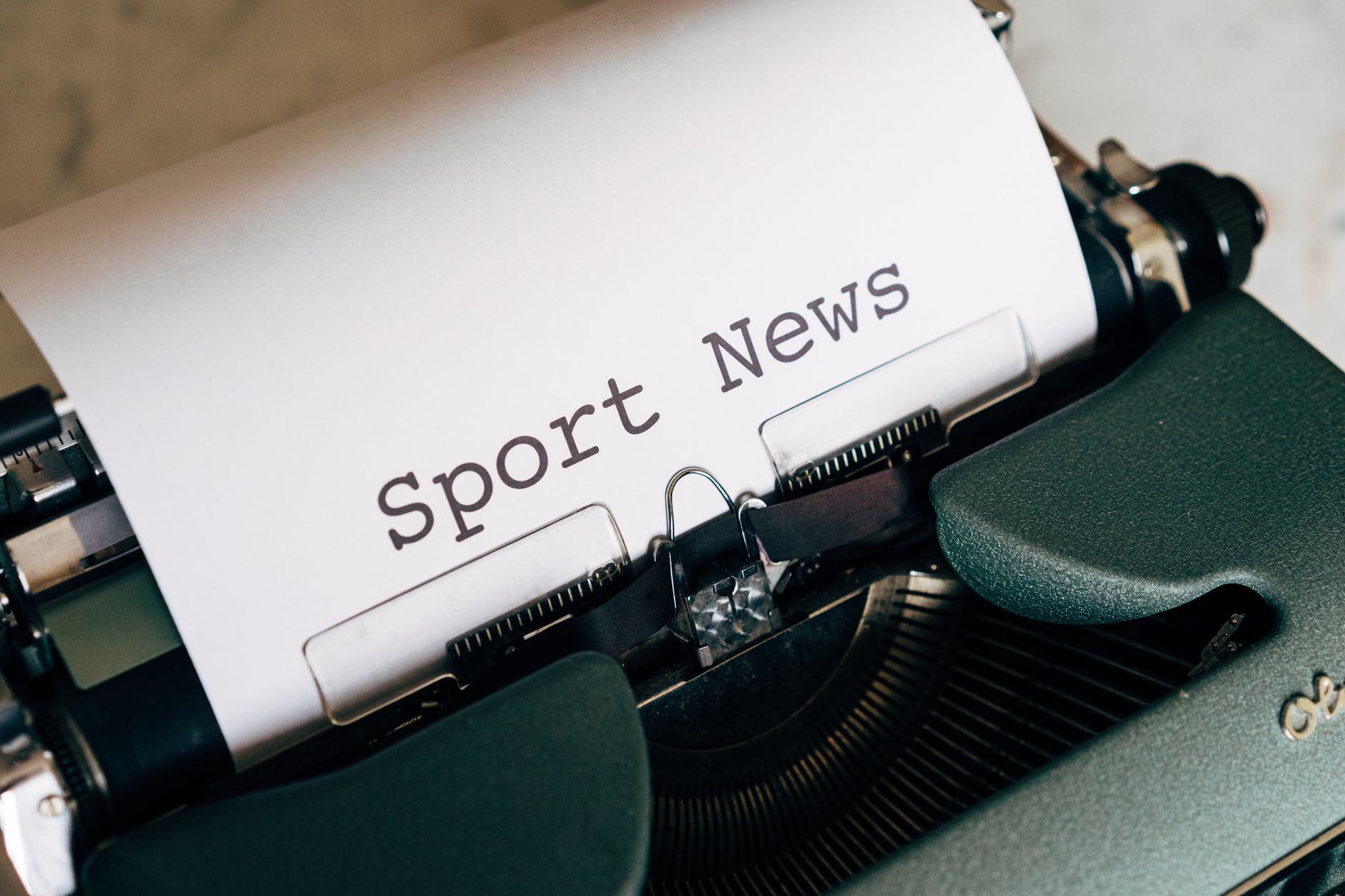 Close-up of a vintage typewriter with 'Sport News' typed on paper, evoking retro charm. — Wie verifiziert LuckyHills Casino d